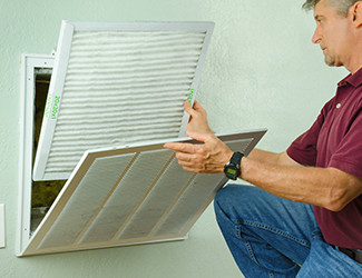 A man changes an air filter in an indoor air unit, a service SAC Mechanical provides