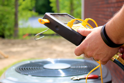 An HVAC contractor checks on an outdoor HVAC system