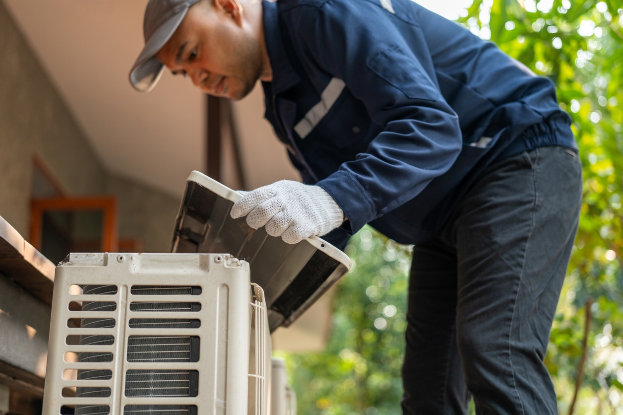An experienced HVAC maintenance technician works on an outdoor unit as part of an HVAC service plan.