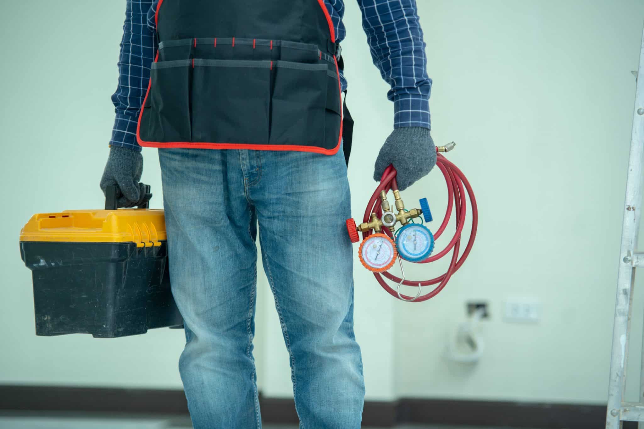 Technician holding HVAC tools, standing indoors, ready for furnace maintenance.