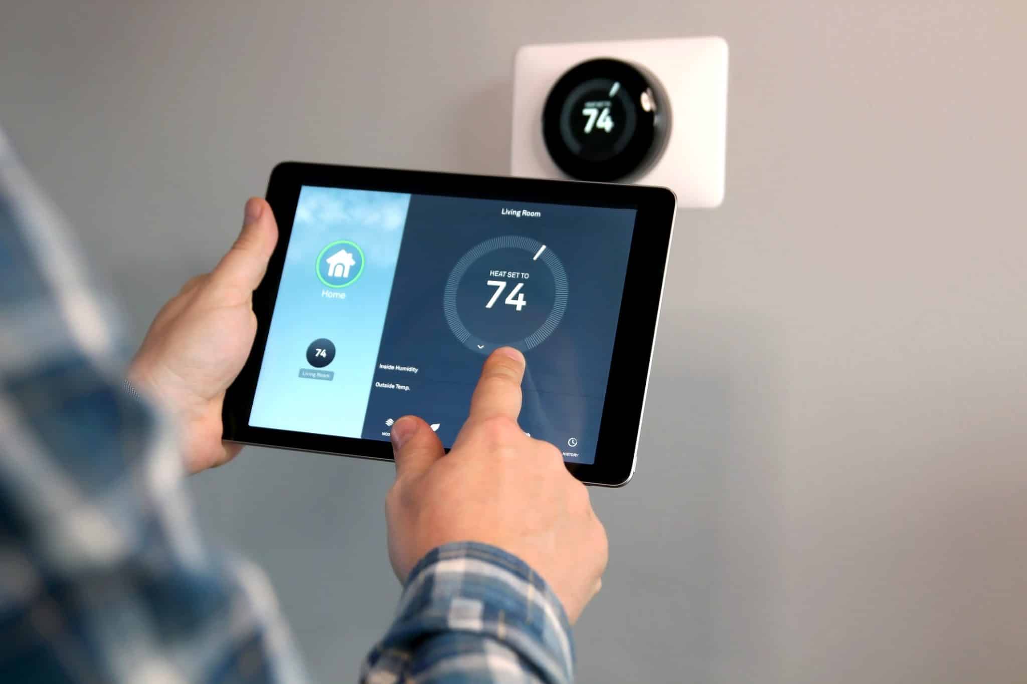 Homeowner using tablet with smart home app to adjust smart thermostat and lower summer cooling costs